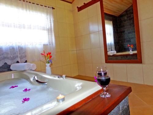 y baño con bañera y una copa de vino. en Pousada Canário Da Terra, en Visconde De Maua