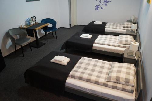 パビャニツェにあるRJ Hotelのベッド3台、テーブル、椅子が備わる客室です。