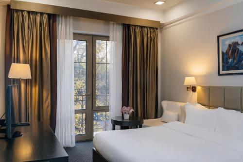 a hotel room with a bed and a window at Ambassador Hotel in Bishkek