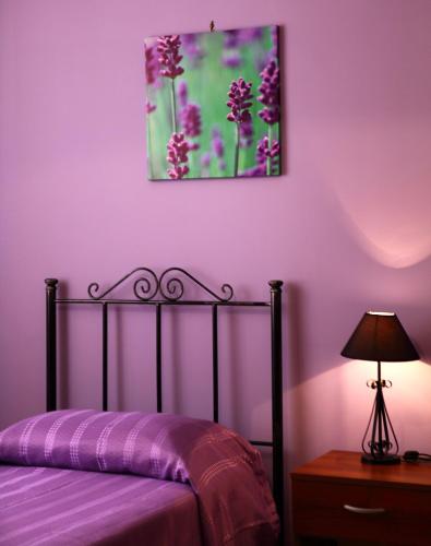 a purple bedroom with a bed and a painting on the wall at Il Cavaliere in Trapani