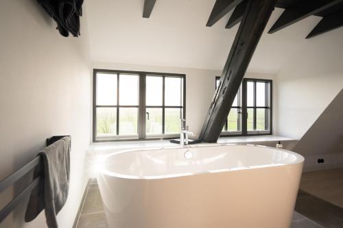 a large white bath tub in a room with windows at Rickmer's Hoff in Pellworm