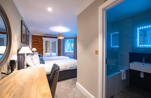 a bedroom with a bed and a table and a bathroom at Cottesmore Hotel Golf & Country Club in Crawley
