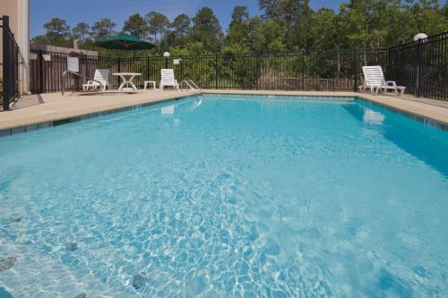 a large blue swimming pool with chairs and a table at Country Inn & Suites by Radisson, Saraland, AL in Saraland