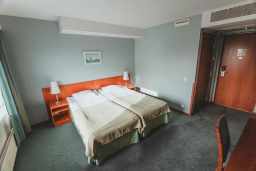a bedroom with a bed and a table and a door at SpaHotel Hamina in Hamina