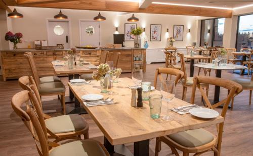 a dining room with wooden tables and chairs at Cottesmore Hotel Golf & Country Club in Crawley
