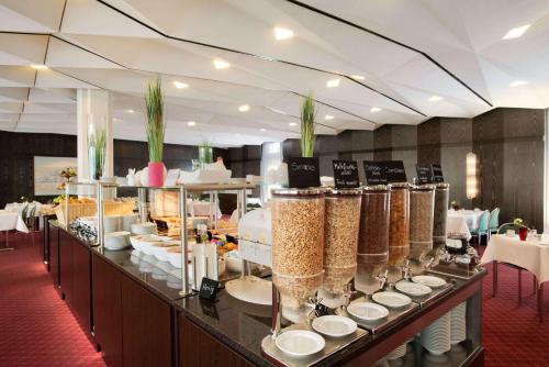 a restaurant with a buffet line with plates and food at Ramada Nürnberg Parkhotel in Nürnberg