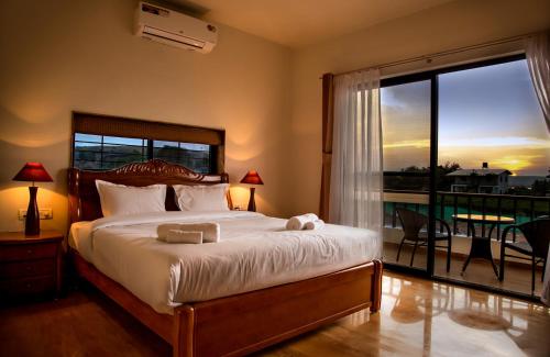 a bedroom with a bed with a view of a balcony at Soma Vineyard Resort -Nashik in Nashik