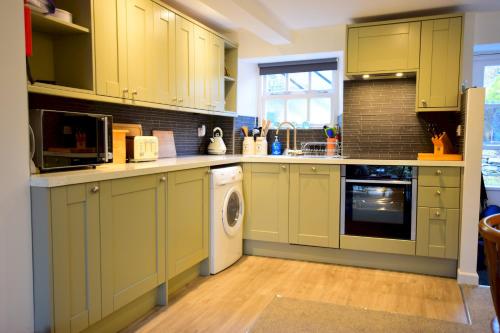 a kitchen with green cabinets and a washer and dryer at Bottom Shop, Elterwater in Chapel Stile