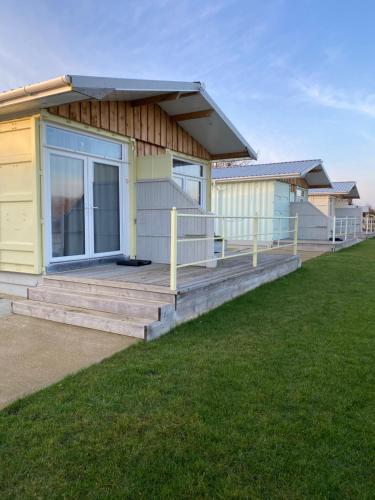 a yellow house with a porch and a lawn at Lake View Lodge in Chichester