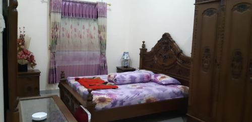 a bedroom with a bed with purple sheets and a dresser at DARRA HOMESTAY TORAJA in Rantepao