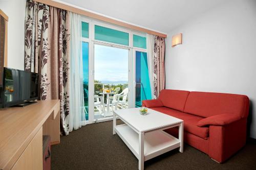 a living room with a red couch and a large window at Magal Maradiso Hotel by Aminess in Njivice