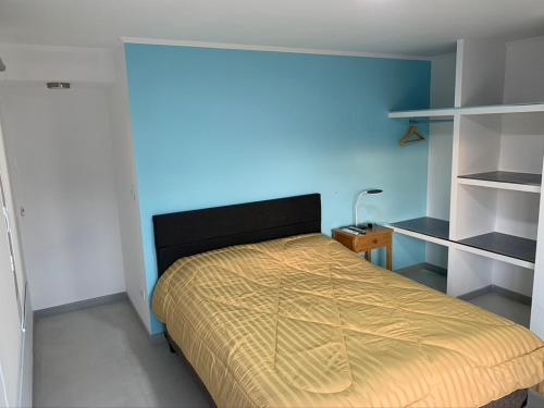 Un dormitorio con una cama con una pared azul. en Complejo Los Cardenales, en Monte Hermoso