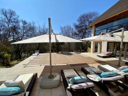 a patio with umbrellas and lounge chairs on a deck at Vaal River YOLO Spaces - Vaal River Bush Villa in Sasolburg