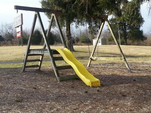 a playground with a slide and a swing at Budget Inn Natural Bridge in Natural Bridge