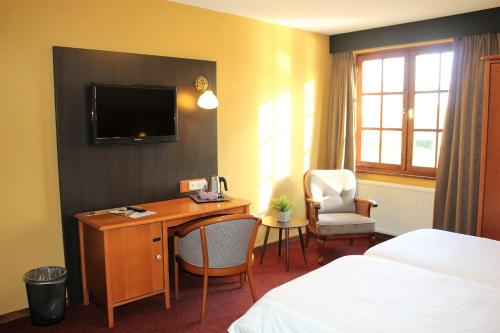 a hotel room with a desk and a bed and a tv at Hotel Restaurant De Roosterhoeve in Roosteren