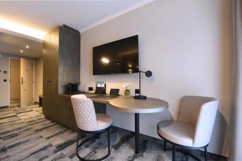 a hotel room with a desk and two chairs at Hotel Charleroi Airport - Van Der Valk in Charleroi