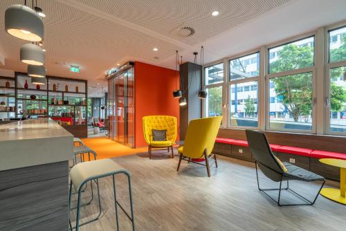 a lobby with yellow chairs and tables in a store at Campanile Frankfurt Offenbach in Offenbach