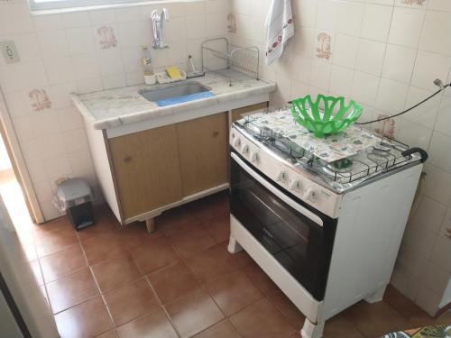 a small kitchen with a stove and a sink at O AP DO FÊ - Apartamento Praia Grande - Vila Tupi in Praia Grande