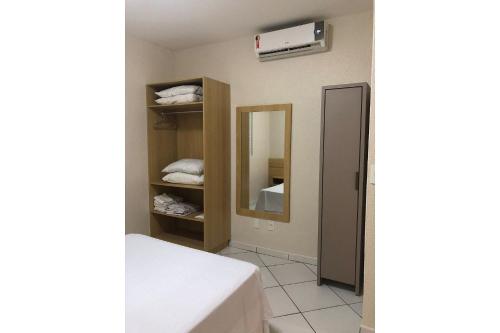 ein kleines Zimmer mit einem Bett und einem Spiegel in der Unterkunft Residencial Gaivotas 09 - 1 Quartos - 30m praia Wifi Cadeira e guarda sol in Florianópolis