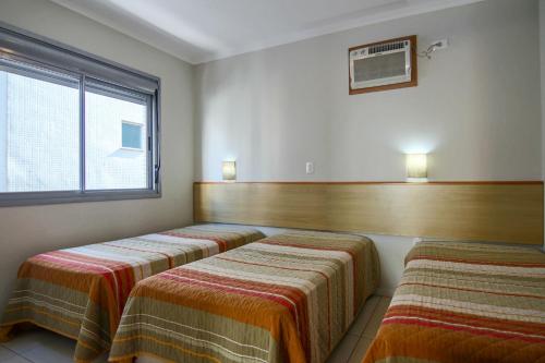 a room with two beds and a window at A Furninha Suites in Torres