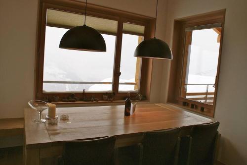 - une table à manger avec des chaises et 2 fenêtres dans l'établissement Perle des Alpes, Bettmeralp, Switzerland, à Bettmeralp
