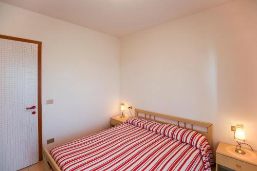 a bedroom with a bed with red and white stripes at Torcello in Bibione
