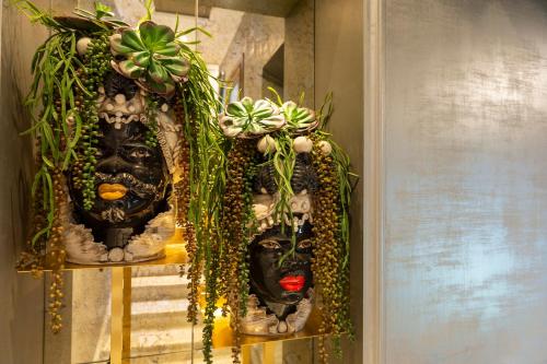 two masks on a shelf with plants on them at Hotel Antico Doge - a Member of Elizabeth Hotel Group in Venice