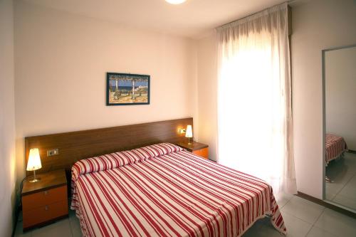 a bedroom with a bed with a striped blanket and a window at Ducale in Bibione