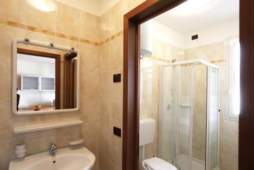 ein Bad mit einer Dusche, einem Waschbecken und einem Spiegel in der Unterkunft Quercia Lido Altanea in Caorle