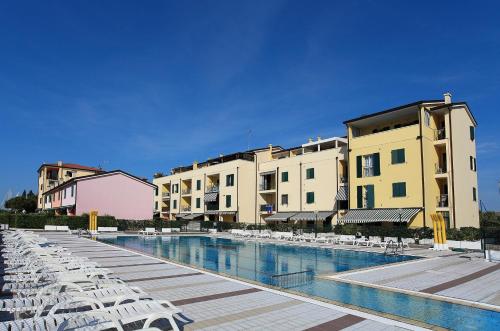 un hotel con una piscina con sillas y edificios en Albatros, en Caorle