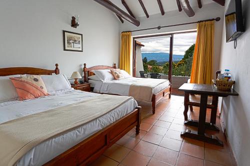 a bedroom with two beds and a large window at Hotel Mesón de los Virreyes in Villa de Leyva