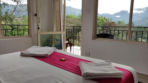 a bedroom with a bed with a red blanket and two windows at Green Tea View in Munnar