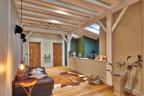 a living room with a leather couch and wooden ceilings at BEL AIR MAISON D'HOTES DES LANDES in Castets