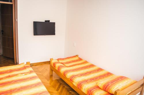 a room with two beds and a tv on a wall at Aparment Theatre in Niš