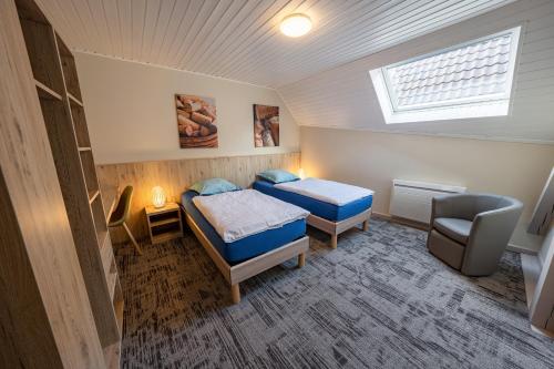 ダンバッハ・ラ・ヴィルにあるChambres d'hôtes Ruhlmannのベッド2台と窓が備わる小さな客室です。