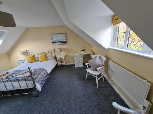a bedroom with a bed and a desk and windows at Self contained annexe in pretty Suffolk village in Bury Saint Edmunds