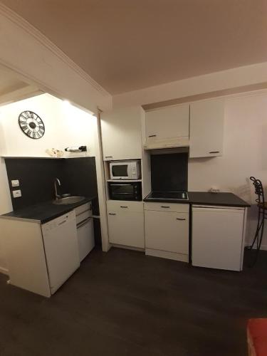 une cuisine avec des placards blancs et une horloge murale dans l'établissement Le BELVEDERE 2 - Acces Direct Plage, à Argelès-sur-Mer