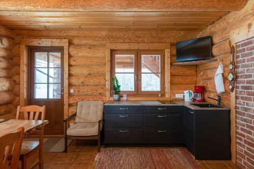 a kitchen in a log cabin with a tv on the wall at RosenHausen Puhkemajad in Puugi