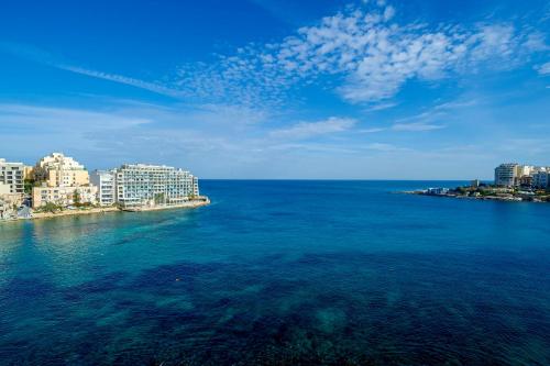 a large body of water with buildings in the background at Spinola Bay top floor seafront 3 bedroom Apartment with panoramic sea views - by Getawaysmalta in St. Julianʼs