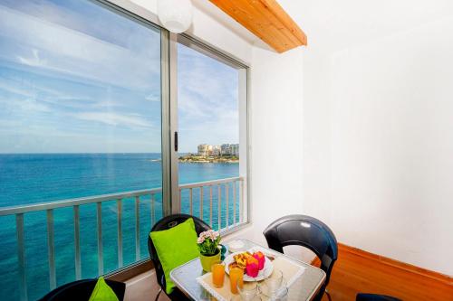 una mesa con vistas al océano desde el balcón en Spinola Bay top floor seafront 3 bedroom Apartment with panoramic sea views - by Getawaysmalta, en San Julián