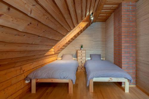 two beds in a room with a wooden ceiling at RosenHausen Puhkemajad in Puugi