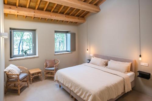 a bedroom with a large bed and two chairs at Casale Tre Gelsi in Cingoli
