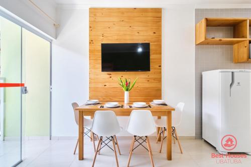 a dining room with a wooden table and white chairs at Estúdios 3 Praias in Ubatuba