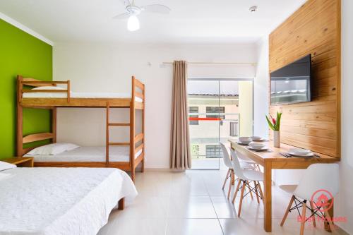 a bedroom with a bed and a desk with a computer at Estúdios 3 Praias in Ubatuba