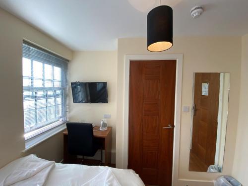 a bedroom with a bed and a desk and a door at Wendover Arms Hotel in High Wycombe