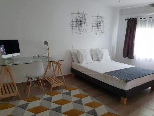 a bedroom with a bed and a desk and a computer at Villa Ilo Majunga in Mahajanga