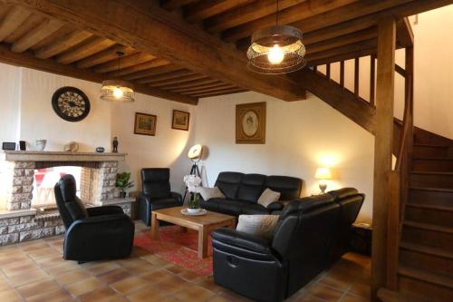 a living room with black leather furniture and a fireplace at Les ammonites gîte de charme en Bourgogne in Guillon