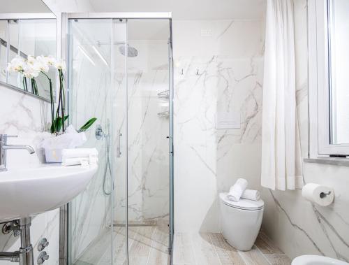 bagno con doccia, lavandino e servizi igienici di Hotel Palace a Lignano Sabbiadoro