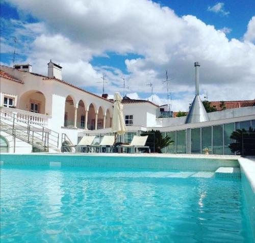 a swimming pool in front of a house at Hotel Solar Dos Mascarenhas in Vila Viçosa