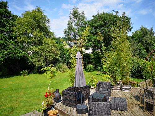 a patio with an umbrella and chairs and a garden at Little Mill, Harbertonford, Totnes. - Entire place. in Totnes